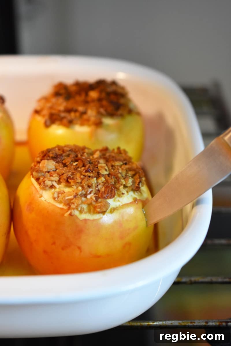 Wholesome Spiced Baked Apples 19 A paring knife is inserted into a baked apple in an open oven.
