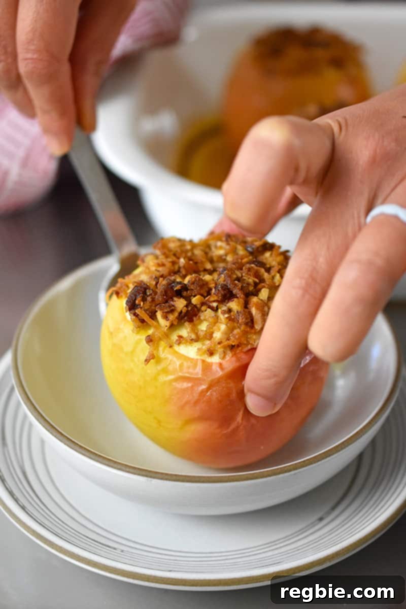 Wholesome Spiced Baked Apples 20 A hand is placing a baked apple in a shallow bowl.