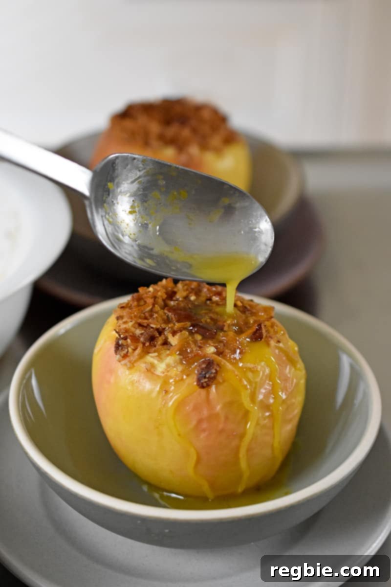 Wholesome Spiced Baked Apples 21 A spoon is pouring the concentrated orange juice onto a baked apple.