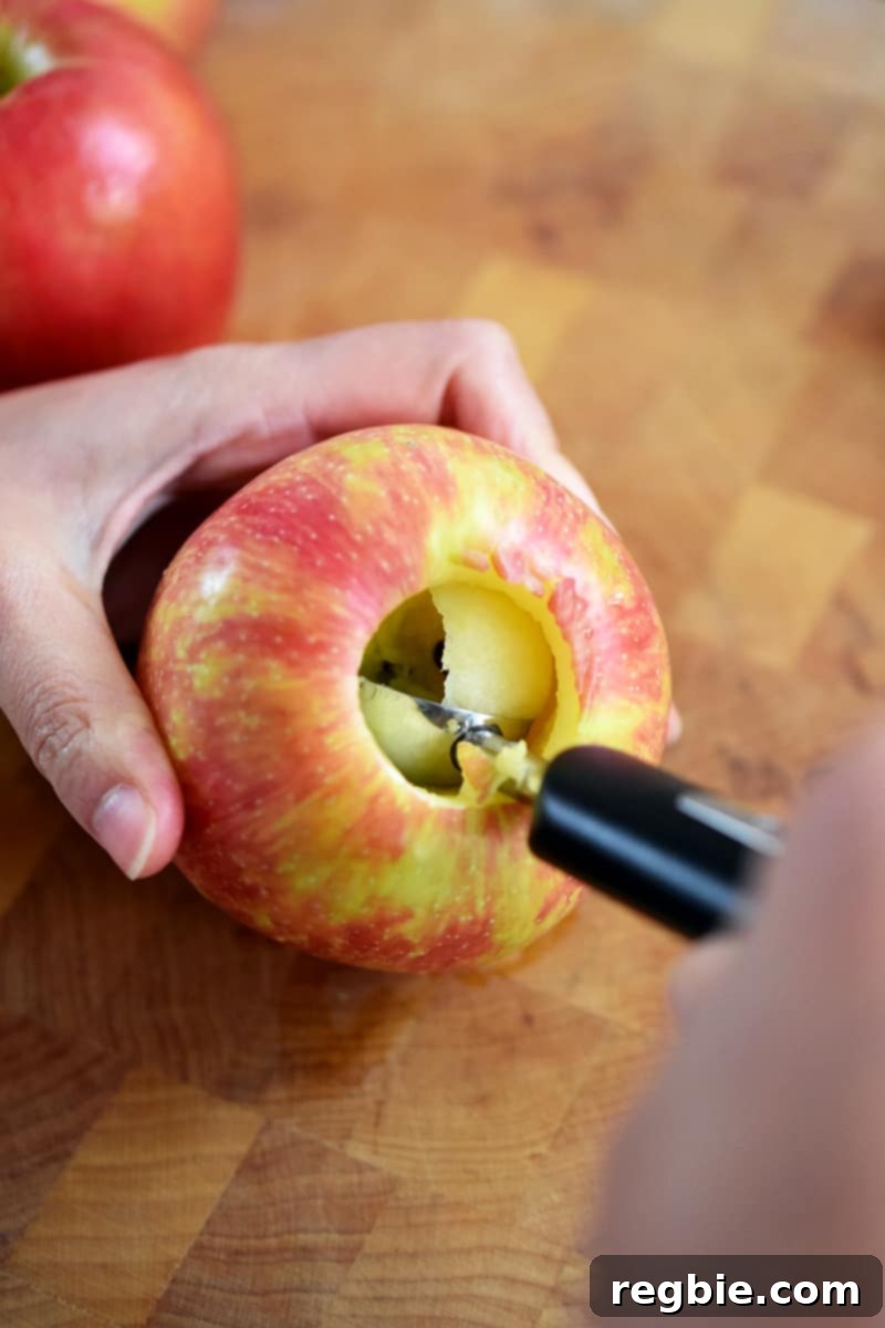 Wholesome Spiced Baked Apples 7 A melon baller is scooping out the stem and core of a Honeycrisp apple.