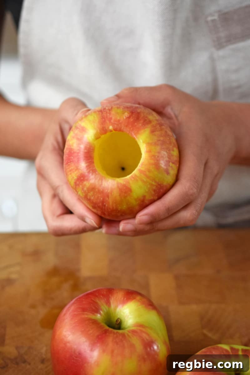 Wholesome Spiced Baked Apples 8 Two hands are holding an apple that has had the core and seeds removed.