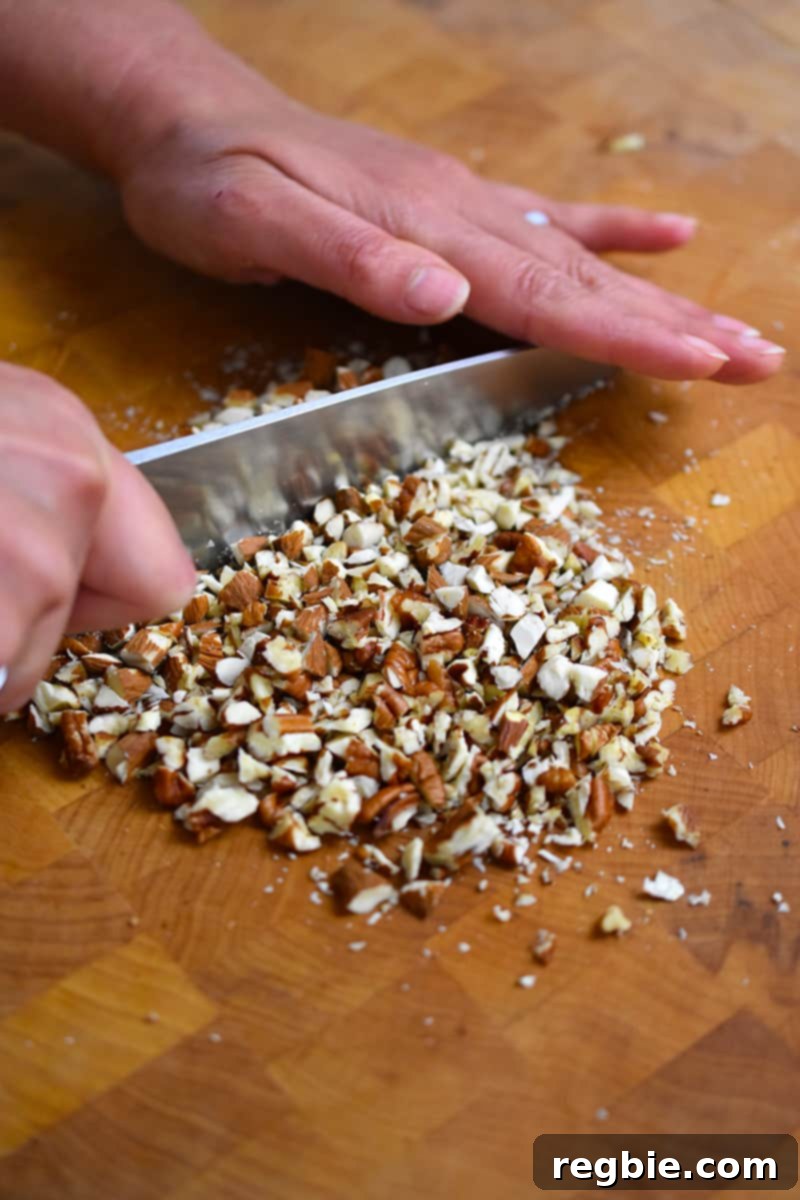Wholesome Spiced Baked Apples 10 Cutting pecans and almonds with a chef's knife on a wooden cutting board