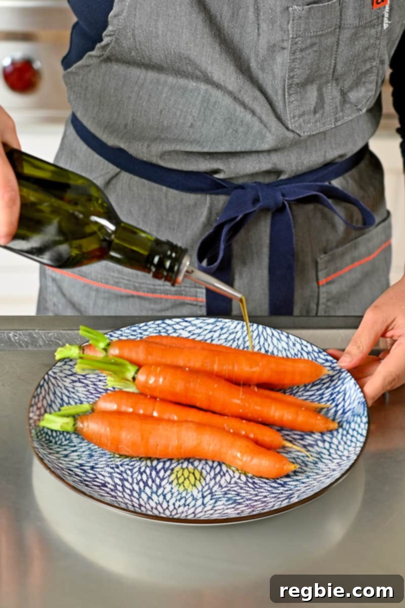 Golden Roasted Air Fryer Carrots 4 Drizzling olive oil from a bottle onto some carrots on a blue plate.