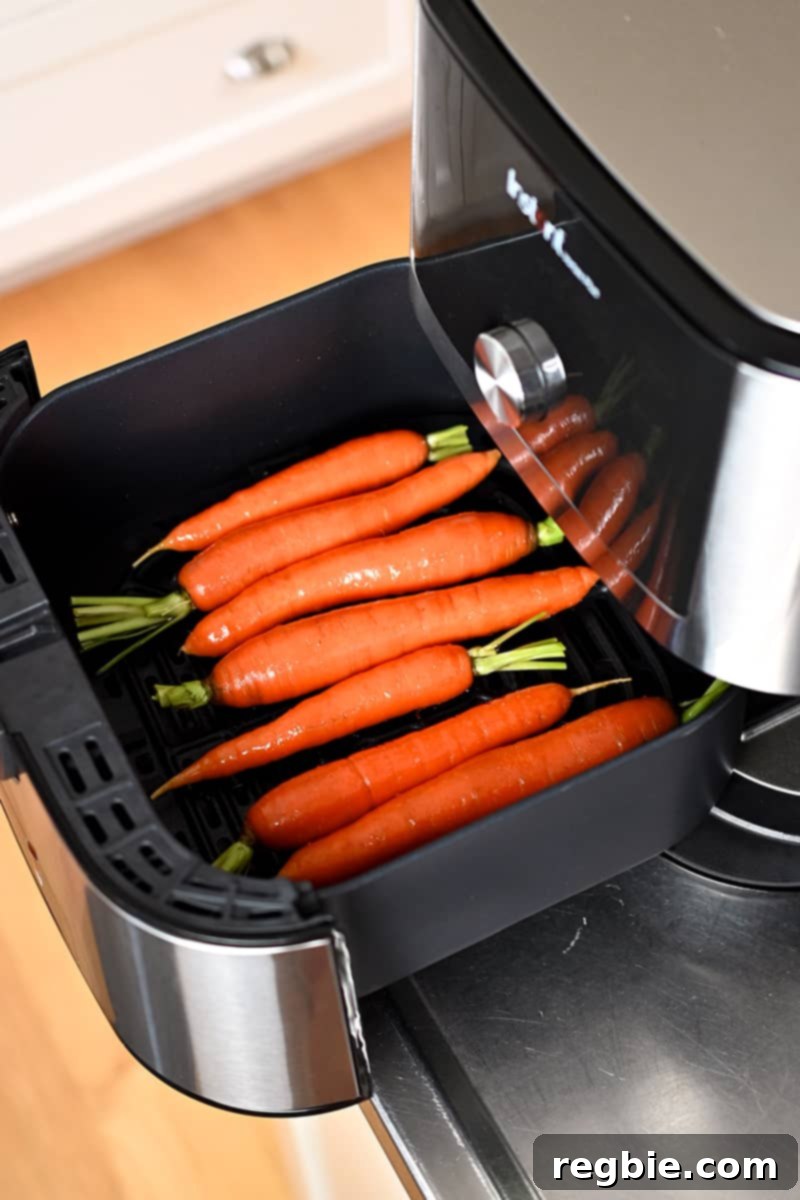 Golden Roasted Air Fryer Carrots 7 Seasoned raw carrots are in an open air fryer basket.