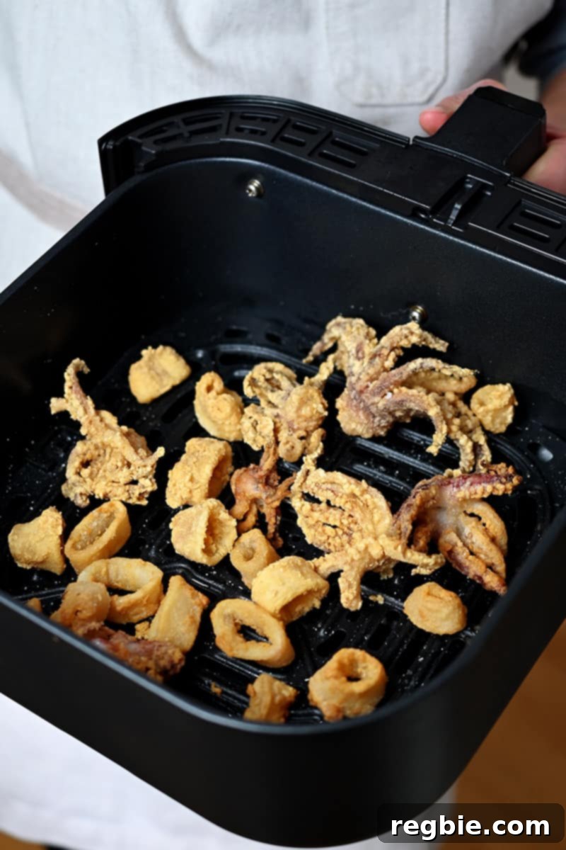 An air fryer basket filled with paleo, gluten-free, and Whole30 fried calamari, ready to be enjoyed as a healthy snack or appetizer.