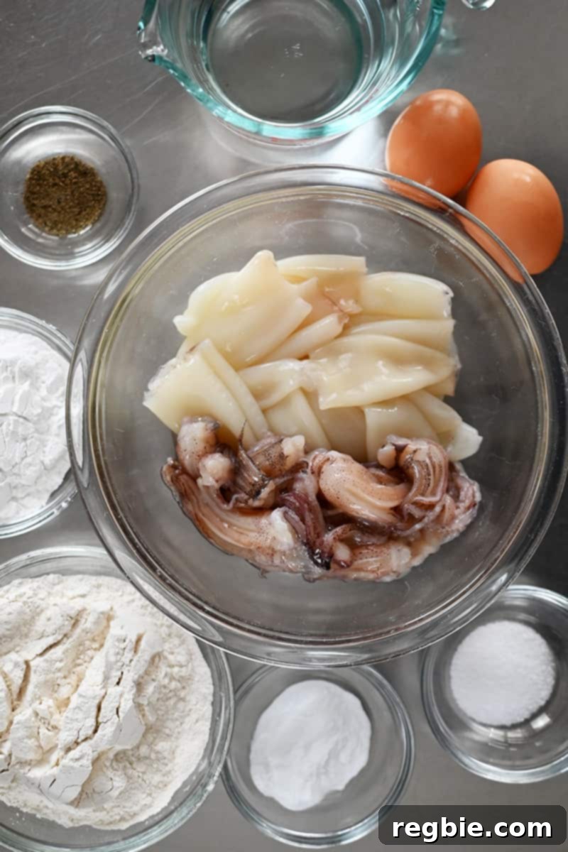An overhead shot of the raw ingredients to make paleo fried calamari in the air fryer or on the stove, neatly laid out on a table.