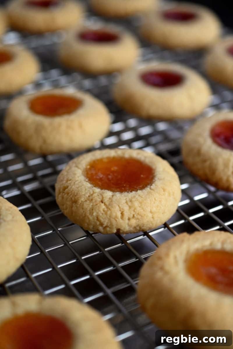 Freshly baked paleo thumbprint cookies are neatly arranged on a wire rack, cooling down.