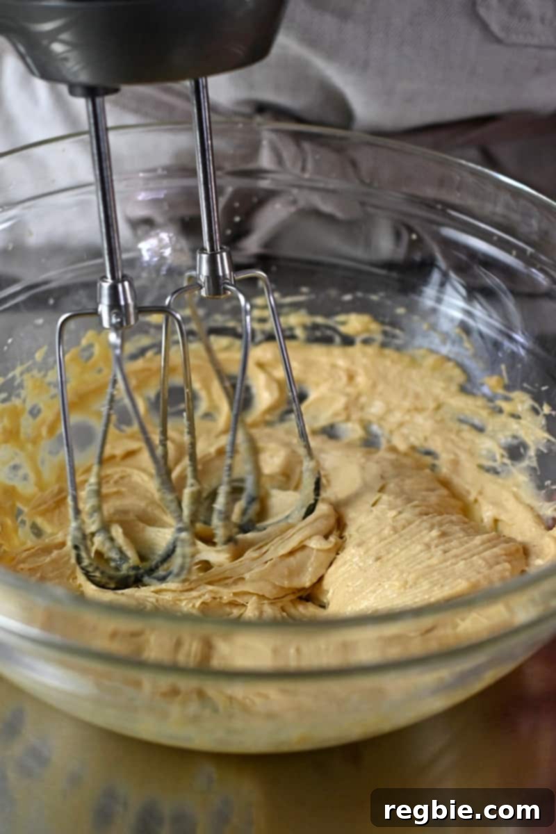 An electric mixer thoroughly combining the wet ingredients for paleo thumbprint cookies into a smooth batter.