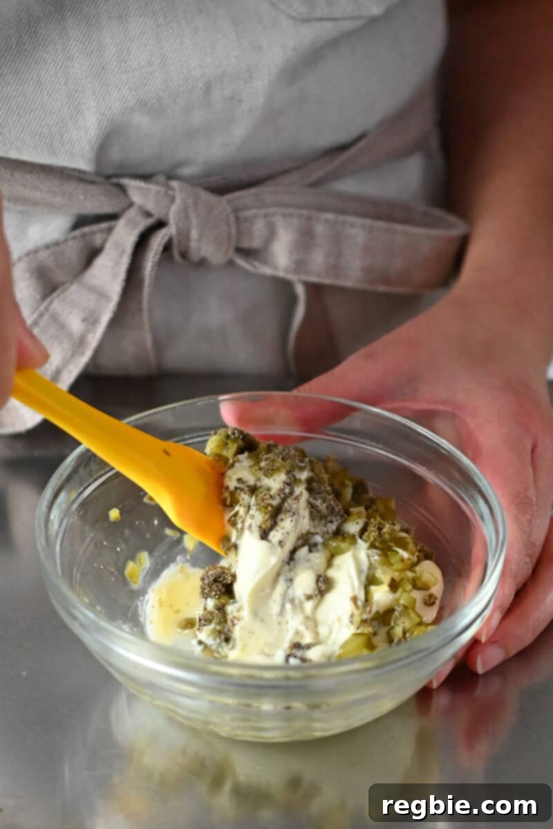 Whip Up Perfect Homemade Tartar Sauce 5 Someone mixing tartar sauce in a clear bowl.