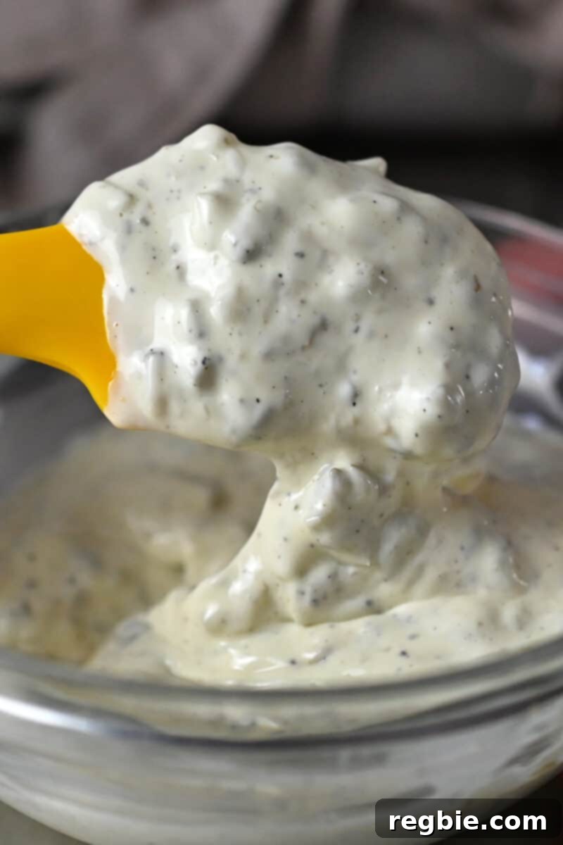 Whip Up Perfect Homemade Tartar Sauce 6 A yellow spatula is mixing tartar sauce in a glass bowl.