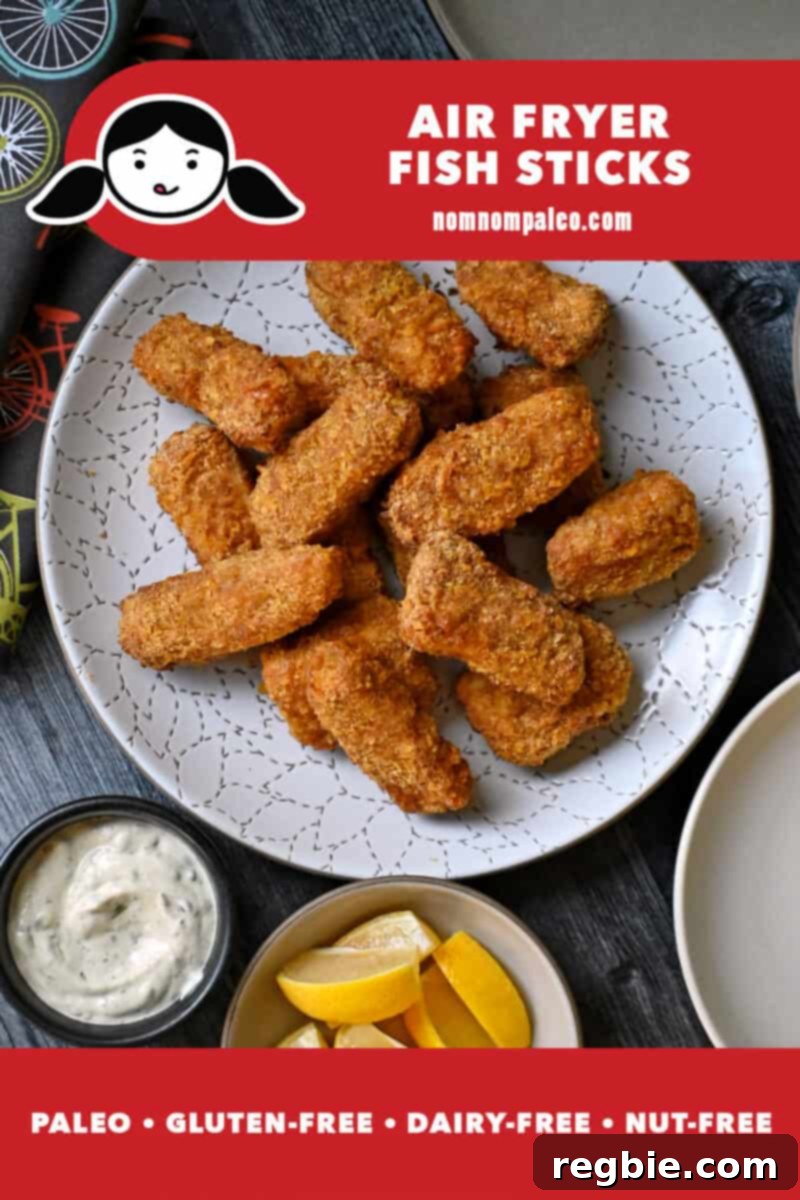 An overhead shot of a plate of air fryer fish sticks next to a bowl of tartar sauce and lemon slices. Golden brown and perfectly crispy.