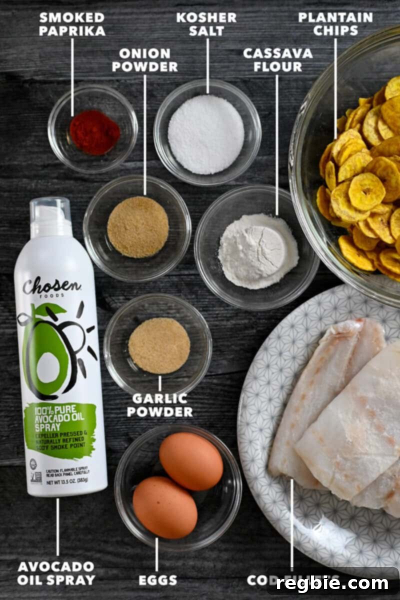 An overhead labelled shot of the raw ingredients for air fryer fish sticks, including cod fillets, plantain chips, eggs, and spices.