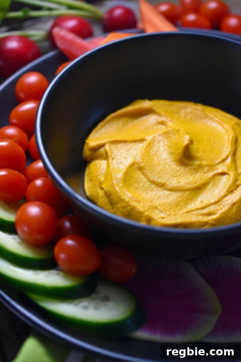 A bowl of the sweet potato and cashew dip surrounded by an array of vegetables.