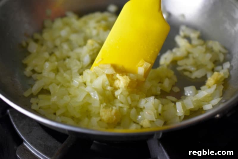Sautéed onions and minced garlic frying in a pan.
