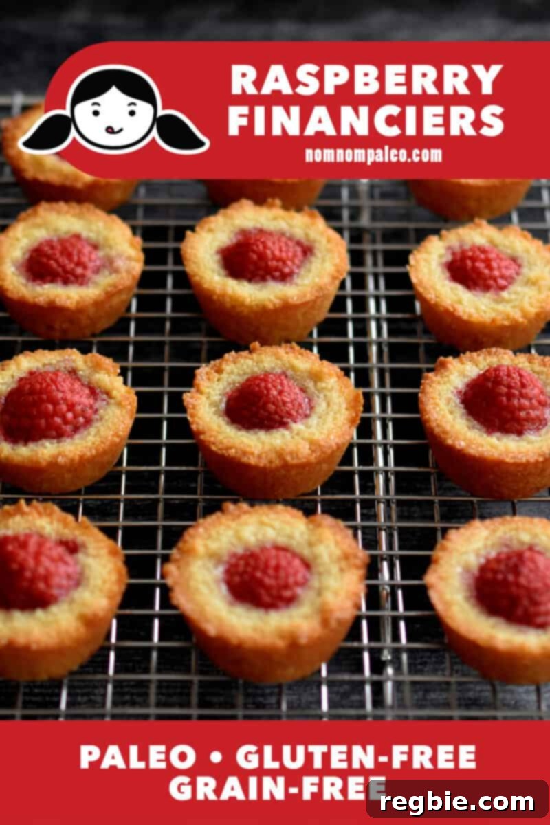 Paleo Raspberry Financiers 2 A stunning close-up of golden-brown paleo and gluten-free raspberry financiers, freshly baked and cooling on a wire rack, showcasing their delicate texture and juicy berry topping.