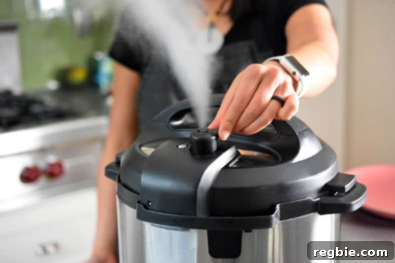 A hand turning the manual release valve on an Instant Pot, with steam vigorously escaping, signifying quick pressure release.