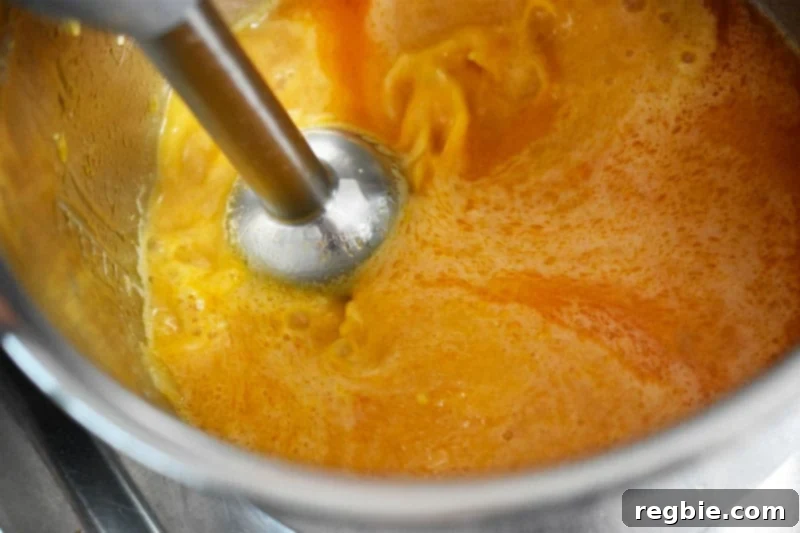 An immersion blender actively puréeing the rich, flavorful contents in the Instant Pot, transforming them into smooth gravy.