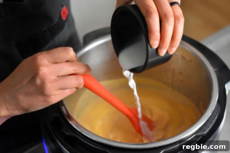 A stream of arrowroot slurry being poured into the simmering gravy in an Instant Pot, to achieve the perfect thickness.