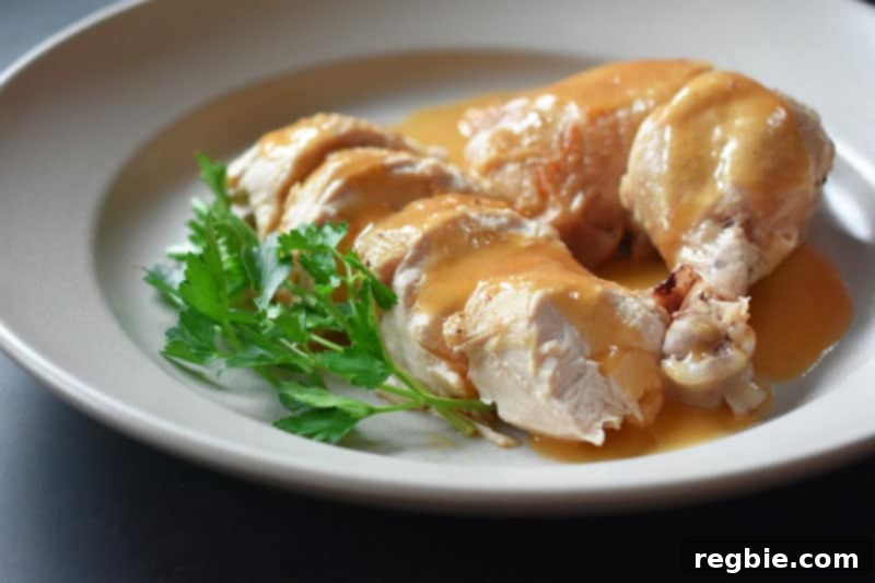 A tempting side view of a platter piled high with carved Instant Pot Whole Chicken and rich, glossy gravy.