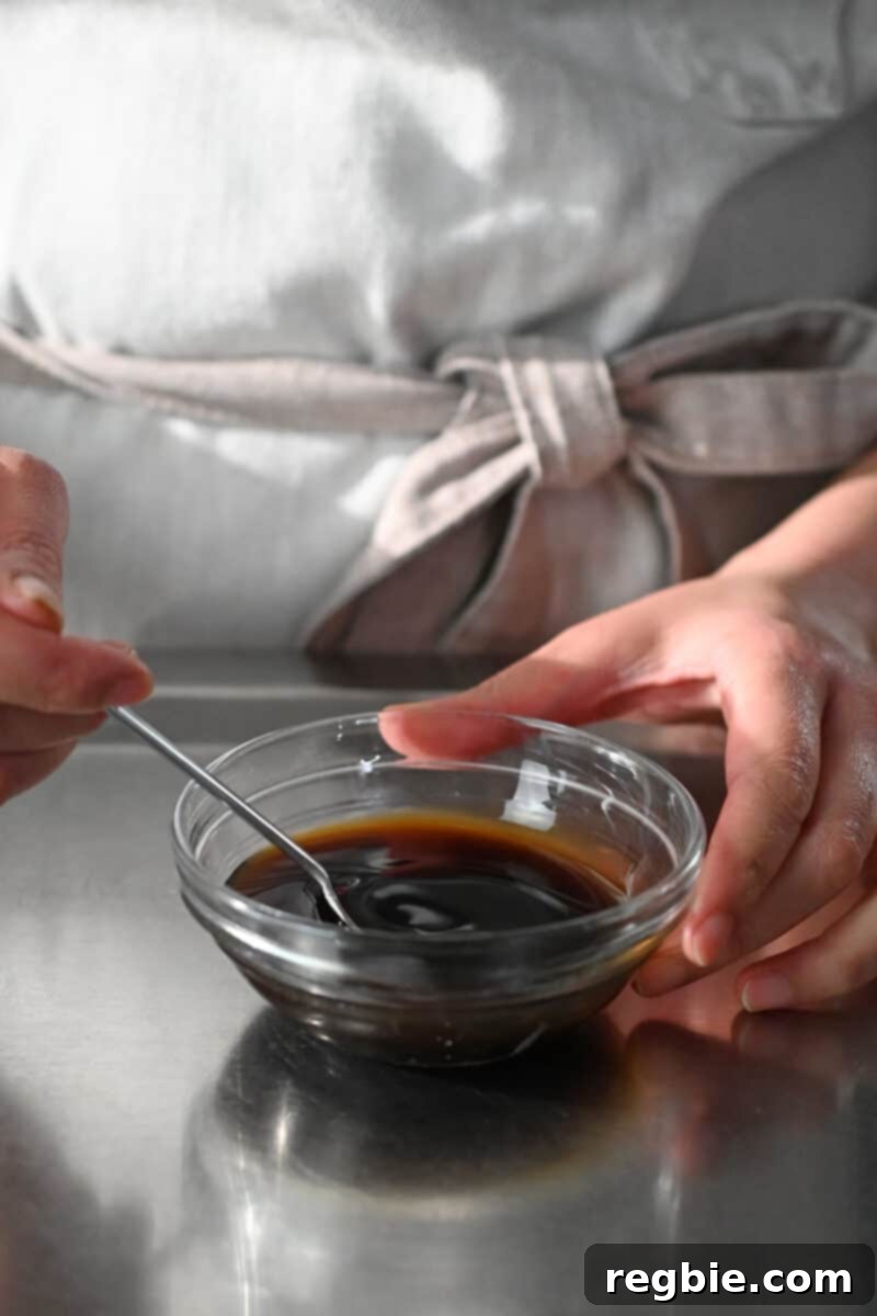 A person in an off-white apron is mixing the sauce for Thai Basil Chicken
