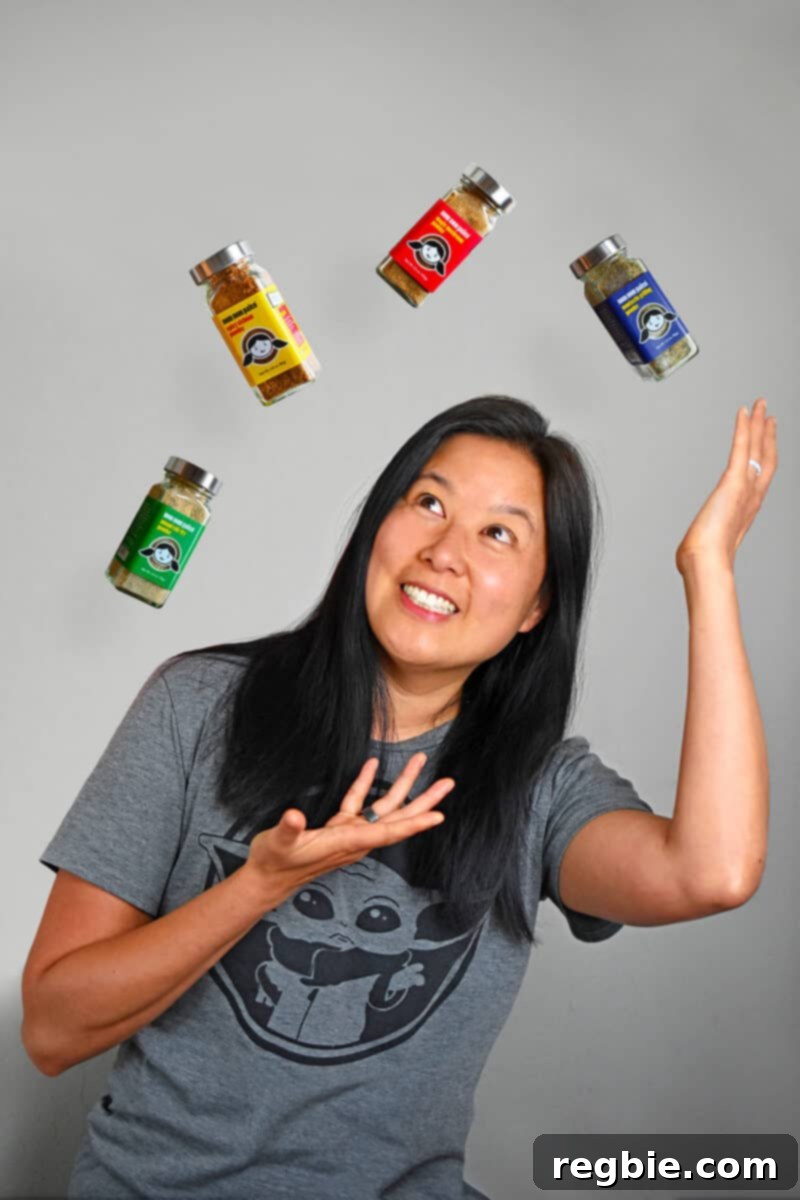 A playful and dynamic photograph of Michelle Tam, captured mid-action as she expertly juggles multiple bottles of the new Nom Nom Paleo spice blends. The image conveys her enthusiasm and the versatility of the product line.