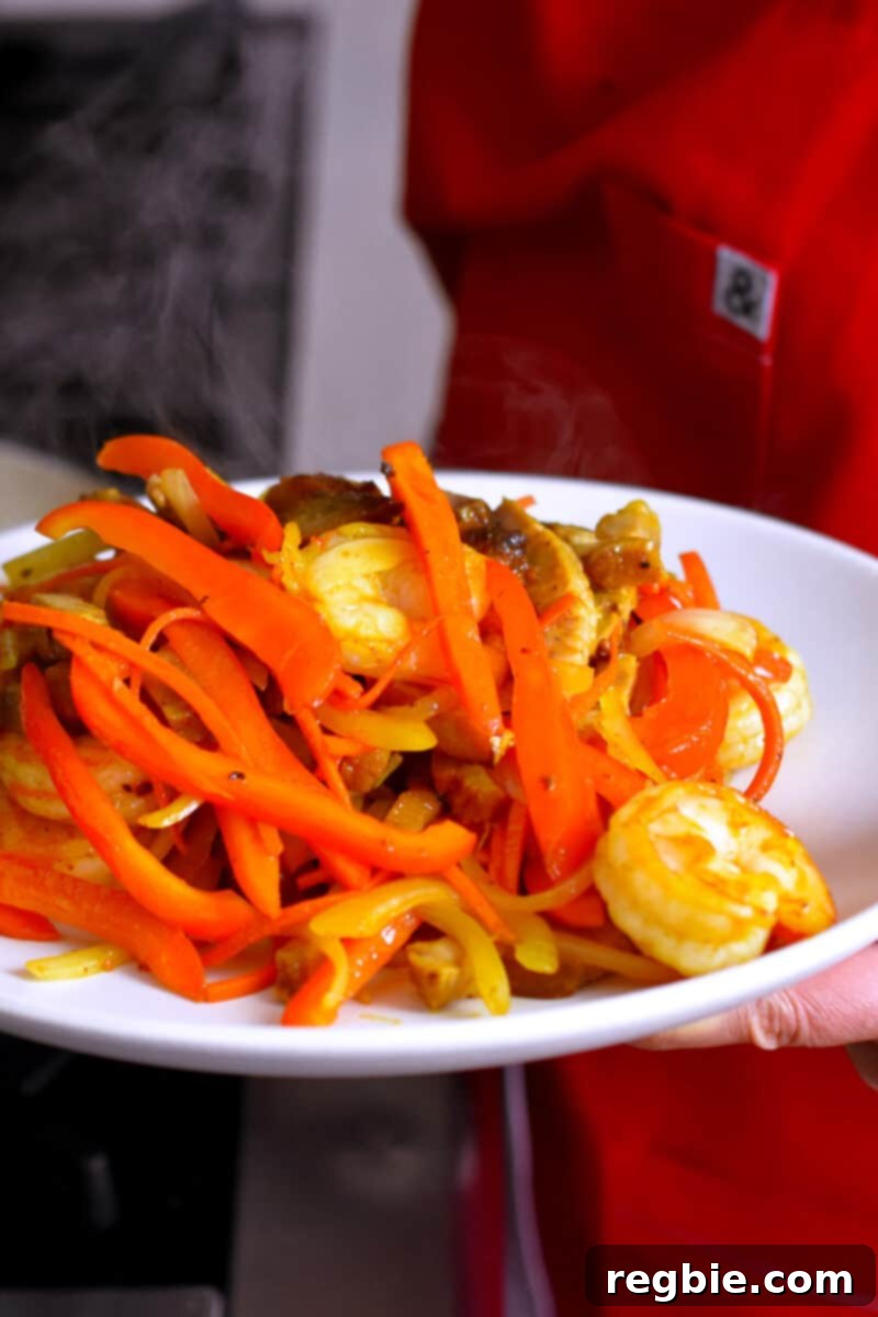 A large plate generously topped with the perfectly cooked meat and tender-crisp vegetables for paleo and Whole30 Singapore noodles.
