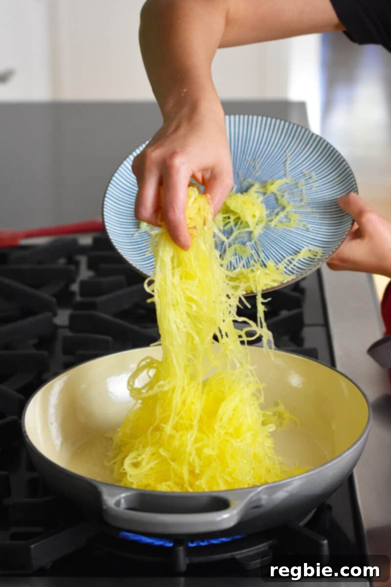 Transferring a plate of beautifully cooked spaghetti squash to an empty skillet, ready for its flavorful transformation.
