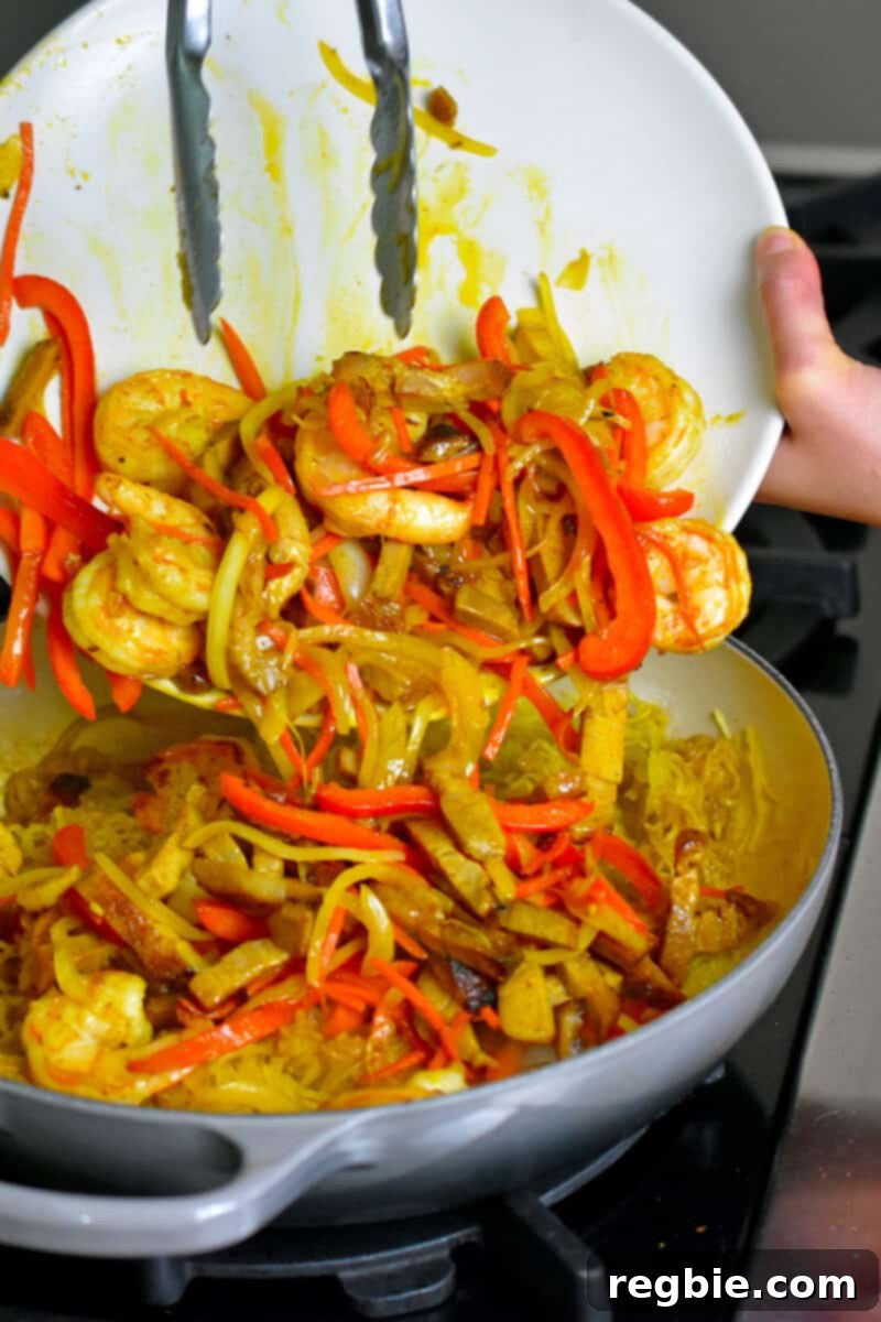 Adding the reserved cooked shrimp, colorful vegetables, and fluffy scrambled eggs to the skillet with perfectly seasoned spaghetti squash.