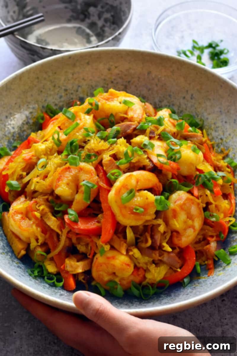 A hand lovingly holding a bowl brimming with flavorful paleo and Whole30 Singapore noodles, ready to be enjoyed.