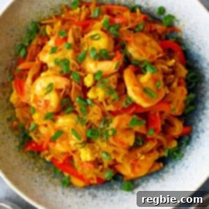 An overhead shot of a bowl of paleo and Whole30 Singapore noodles, topped with shrimp and sliced scallions.