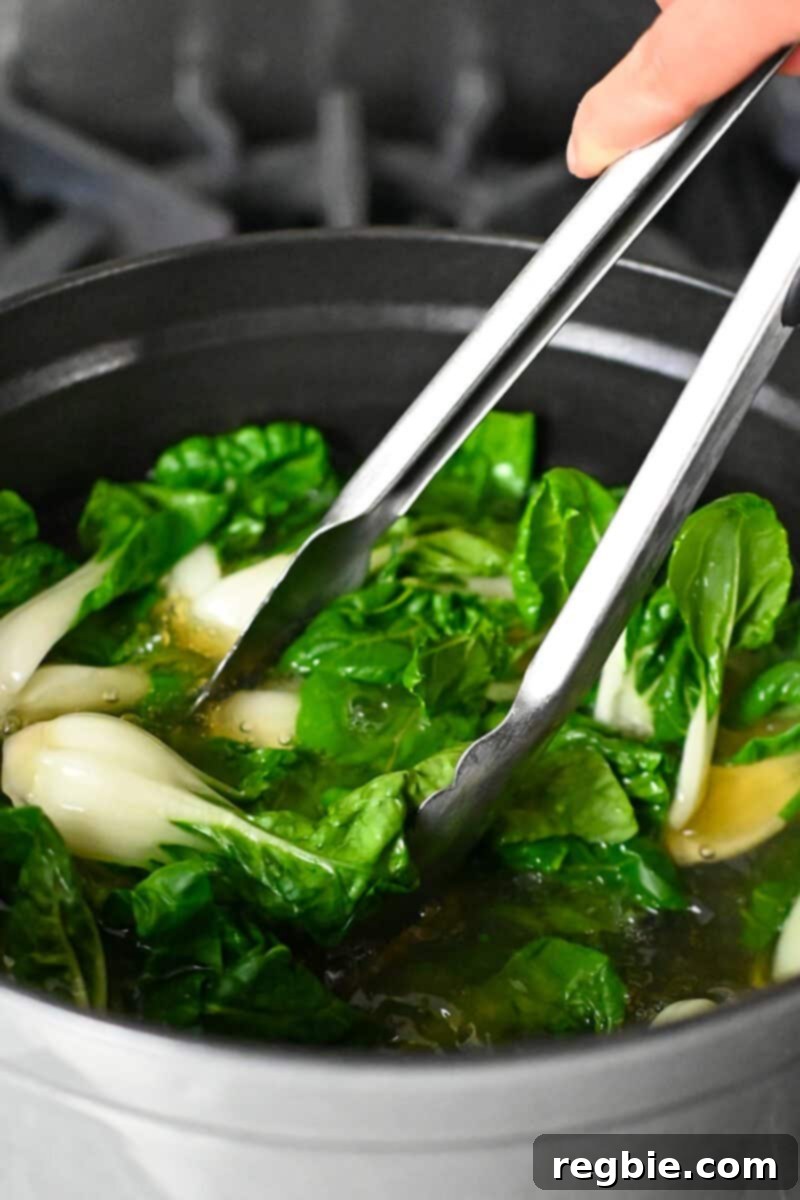 Adding baby Bok Choy to a pot of simmering chicken broth for a quick cook.