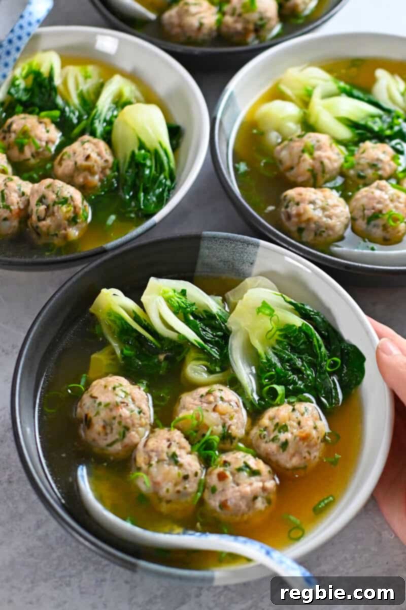 A side view of four bowls of Nom Nom Paleo's wonton soup, garnished with green onions and ready to be enjoyed.