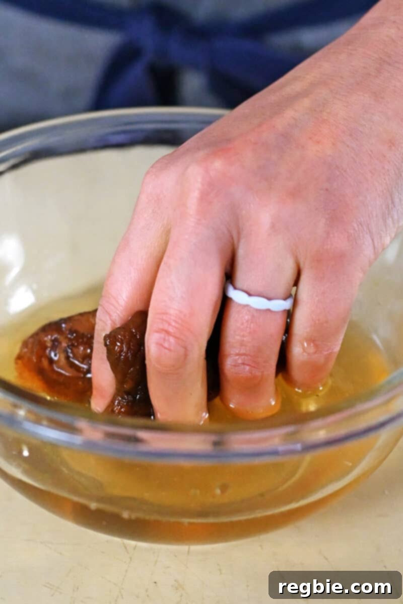A hand is grabbing some dried shiitake mushrooms from a bowl of water, demonstrating rehydration.