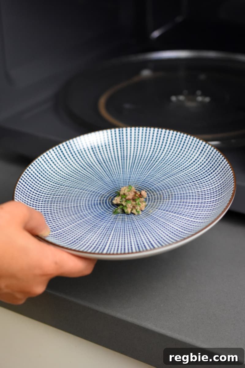 A small patty of cooked meatball meat on a blue and white plate, used for tasting and adjusting seasoning.