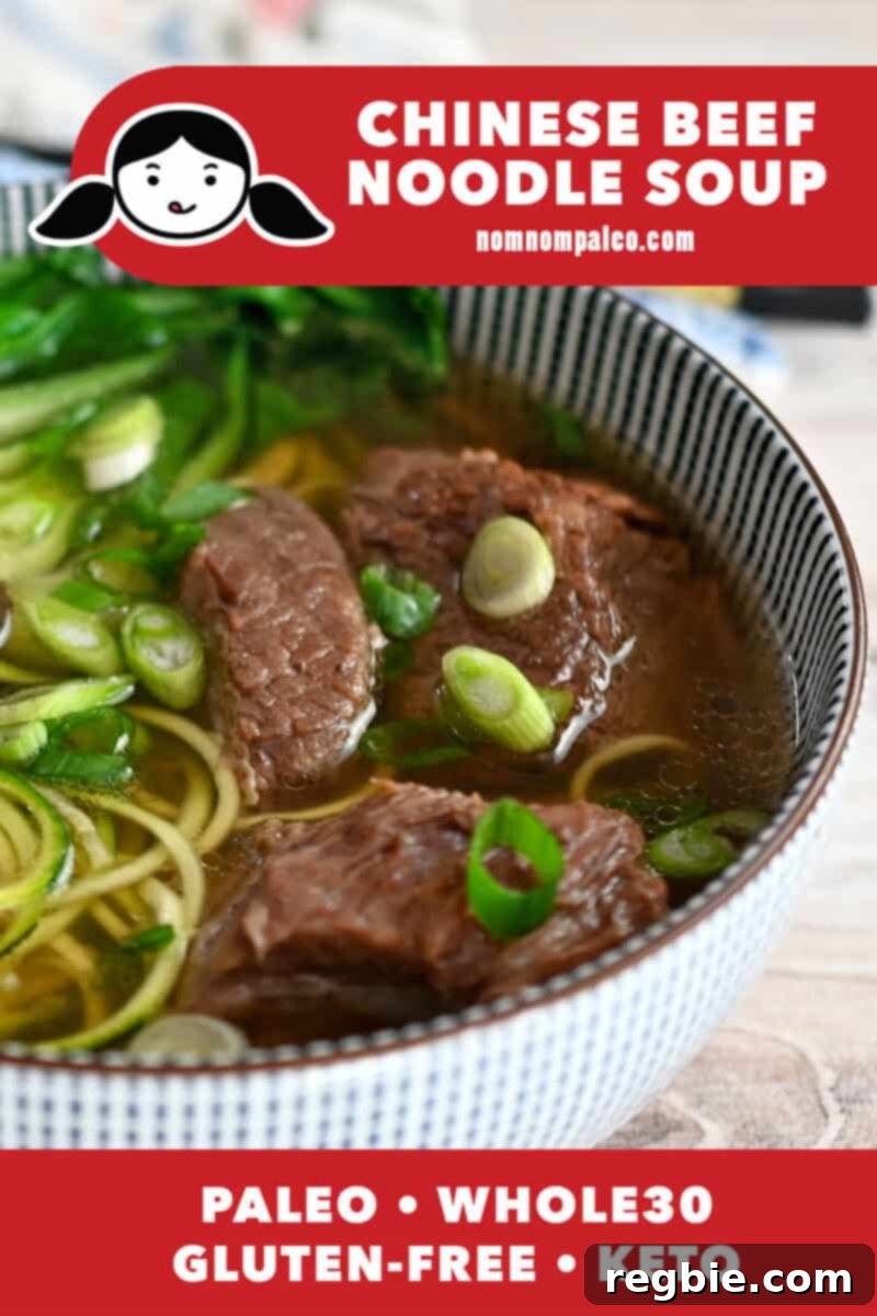 A closeup shot of a blue bowl filled with paleo, Whole30, and keto Chinese beef noodle soup, garnished with fresh herbs.