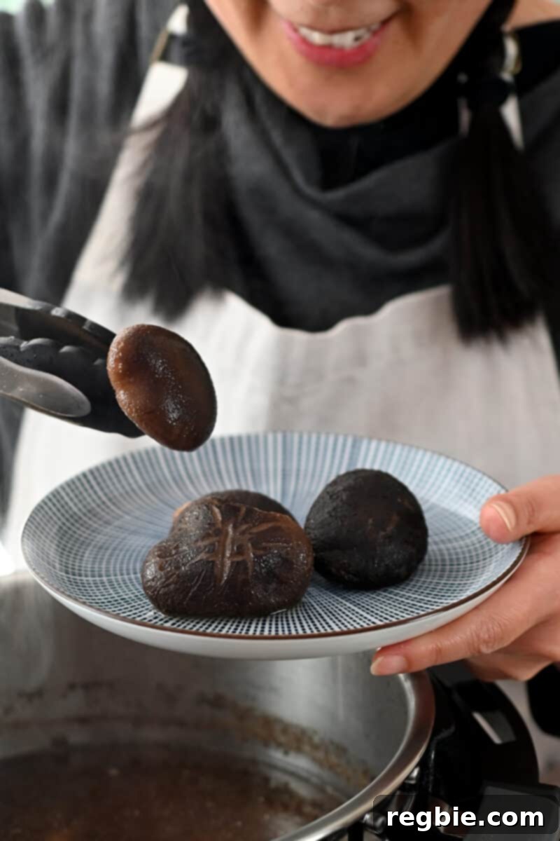 A smiling Asian person is placing cooked shiitake mushrooms on a blue and white plate, preparing them for serving.
