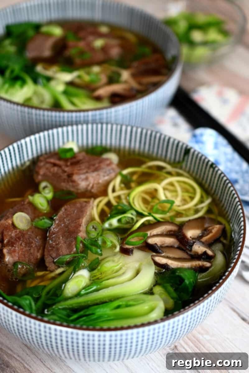 Two bowls of Chinese Beef Noodle Soup, a paleo, Whole30, keto and gluten-free version, beautifully arranged.
