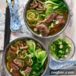 An overhead shot of two bowls filled with paleo, Whole30, gluten-free, and keto Chinese beef noodle soup, ready to be enjoyed.