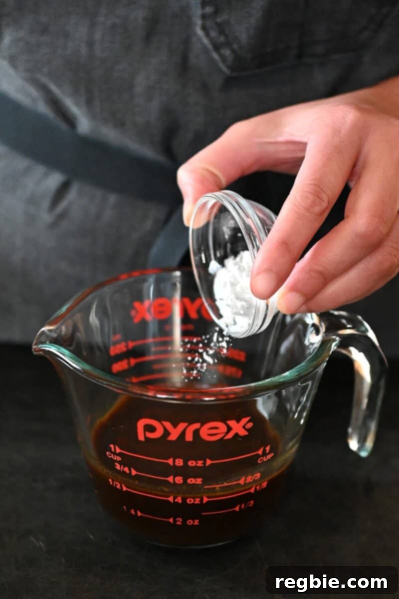 Wholesome Enoki Beef Wraps 15 Adding arrowroot powder into a measuring cup filled with All-Purpose Stir-Fry Sauce, preparing the sauce.
