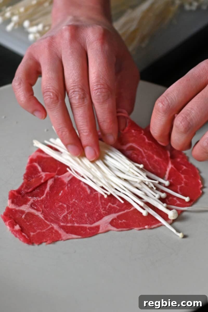 Wholesome Enoki Beef Wraps 7 A small stack of enoki mushrooms is placed on a paper thin slice of beef, ready for rolling