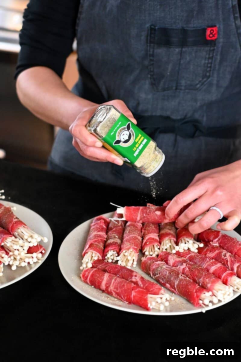 Wholesome Enoki Beef Wraps 10 A hand sprinkling Umami Stir-Fry Powder on some beef and enoki rolls, preparing them for cooking.