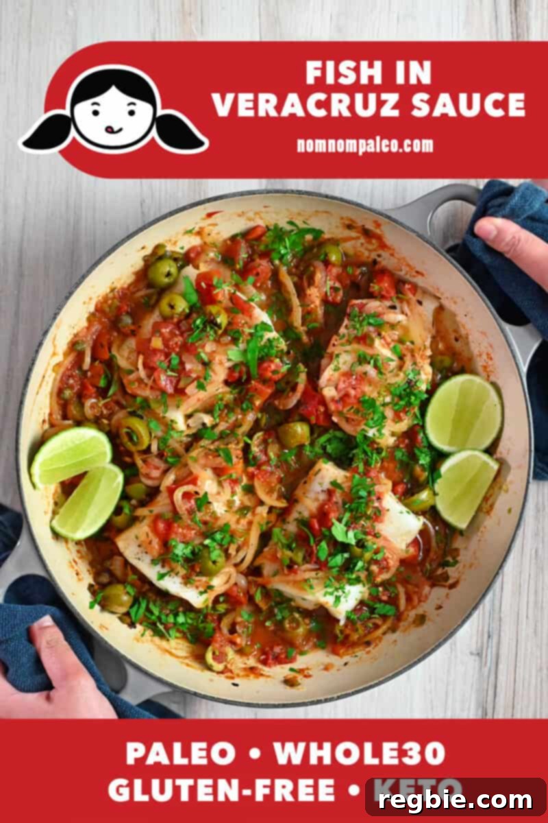 An overhead shot of a skillet filled with flaky white fish fillets perfectly simmered in a rich, vibrant Veracruz sauce, garnished with fresh herbs and lime wedges.