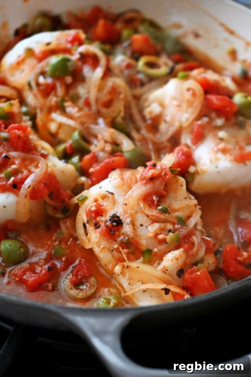 A close-up of beautifully cooked, flaky white fish fillets immersed in a flavorful homemade Veracruz sauce, showcasing the dish's vibrant appeal.