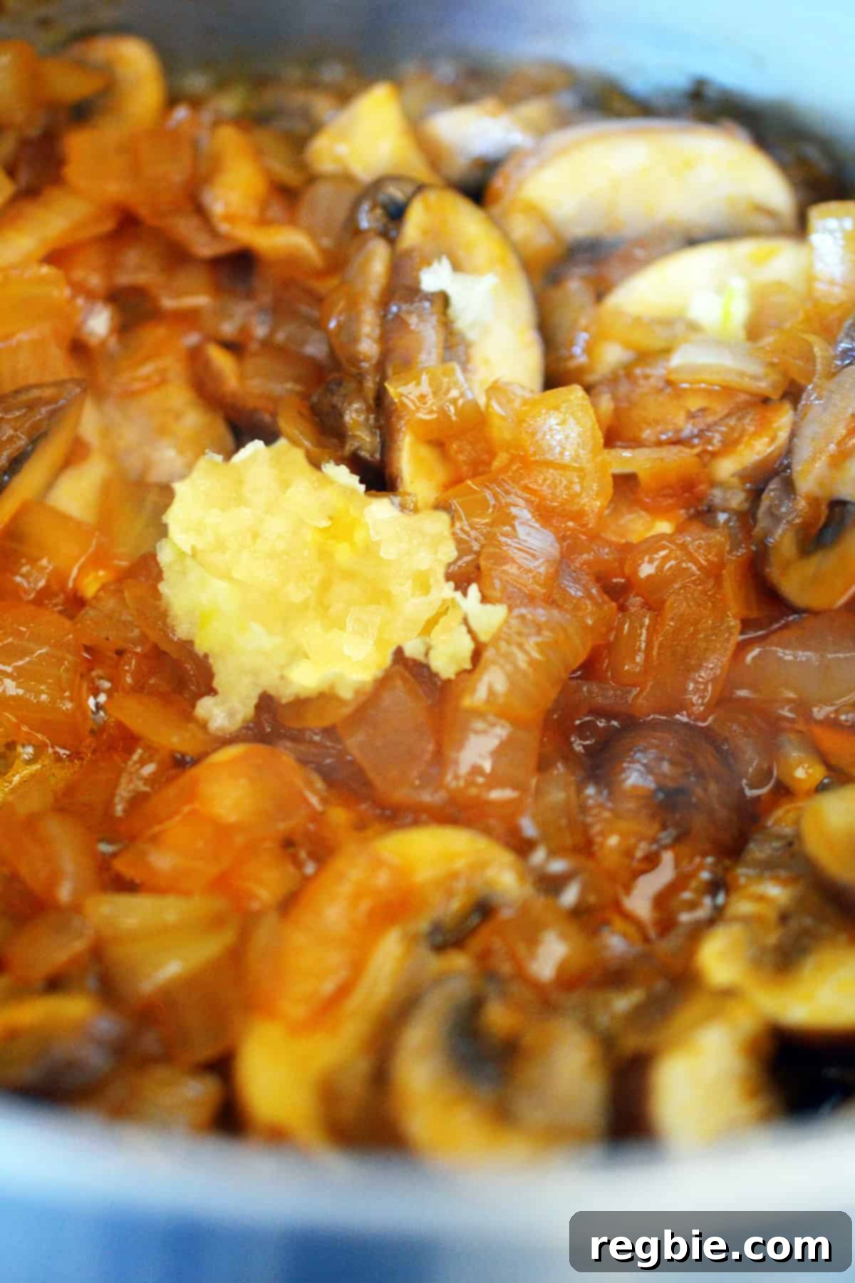 A closeup of minced garlic added to sautéed mushrooms, onions, and the other ingredients for gluten-free gravy.