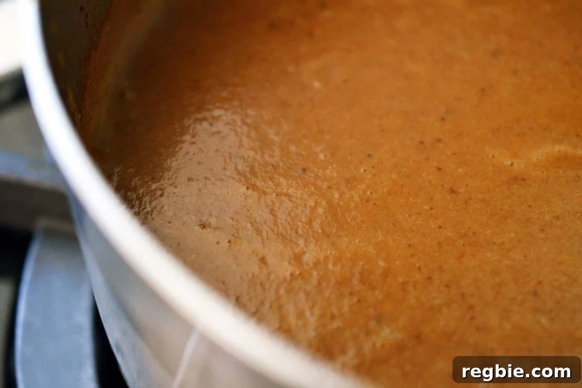 An overhead shot of a saucepan filled with a smooth gluten free gravy that is packed with umami flavor.