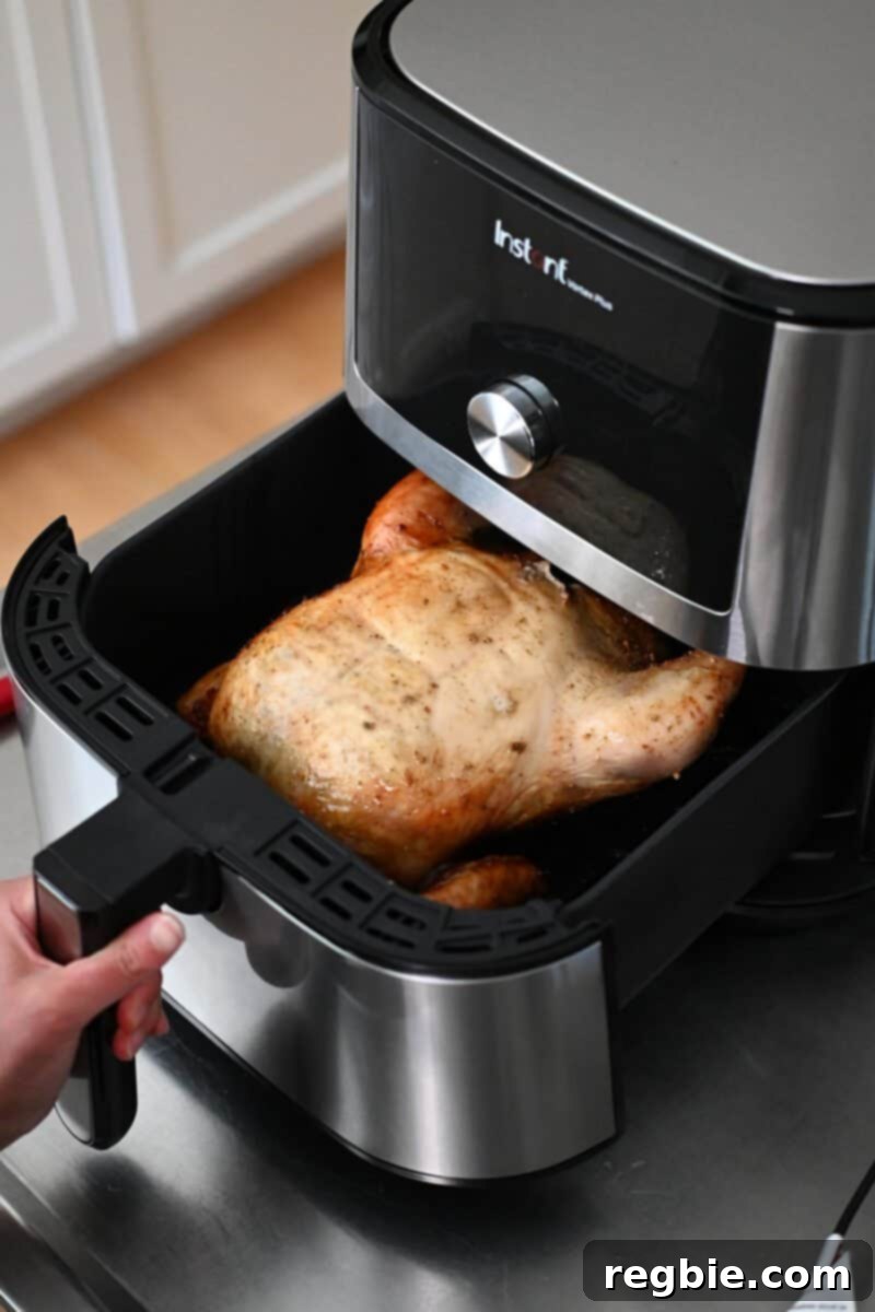 Golden Crispy Air Fried Whole Chicken 13 An open air fryer with a whole chicken inside, now breast side up, finishing its browning phase.