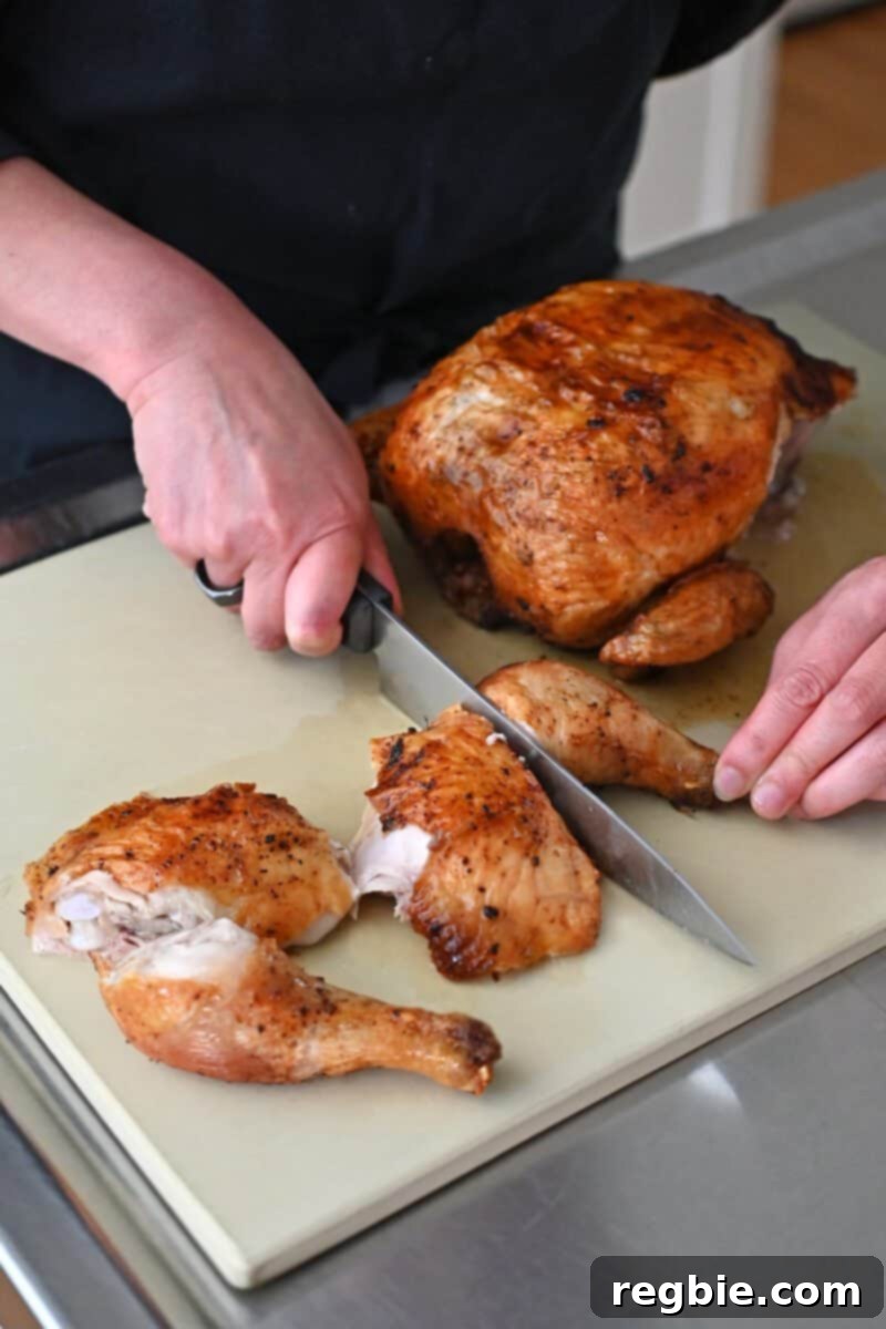 Golden Crispy Air Fried Whole Chicken 15 A person cutting up an air fryer whole chicken on a wooden cutting board, showcasing the juicy interior.