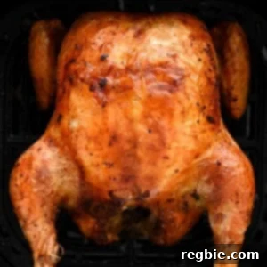 An overhead shot of a golden brown air fryer whole chicken in an air fryer basket, beautifully cooked.