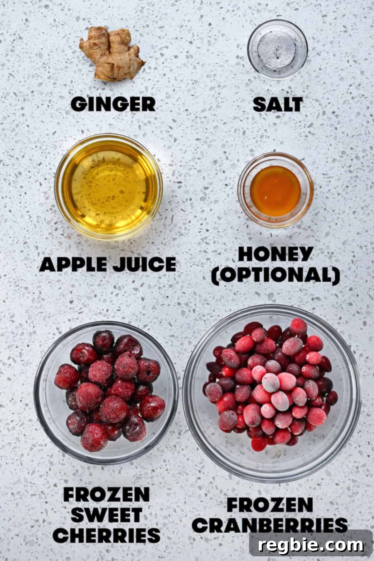 An overhead shot of the raw ingredients to make paleo cranberry sauce with cherries, including frozen berries, apple juice, ginger, and honey.