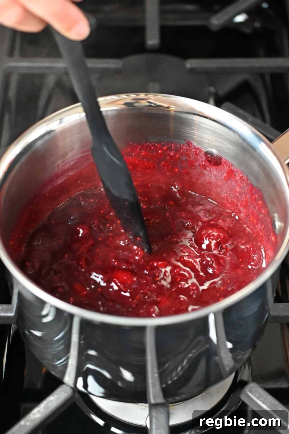 Paleo cranberry cherry sauce in a saucepan, showcasing the correct thick consistency, indicating it's ready to serve.